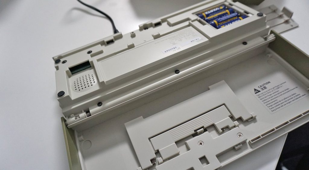 Auf der Unterseite finden sich Batteriefach, Lautsprecher und Aufstellbügel.